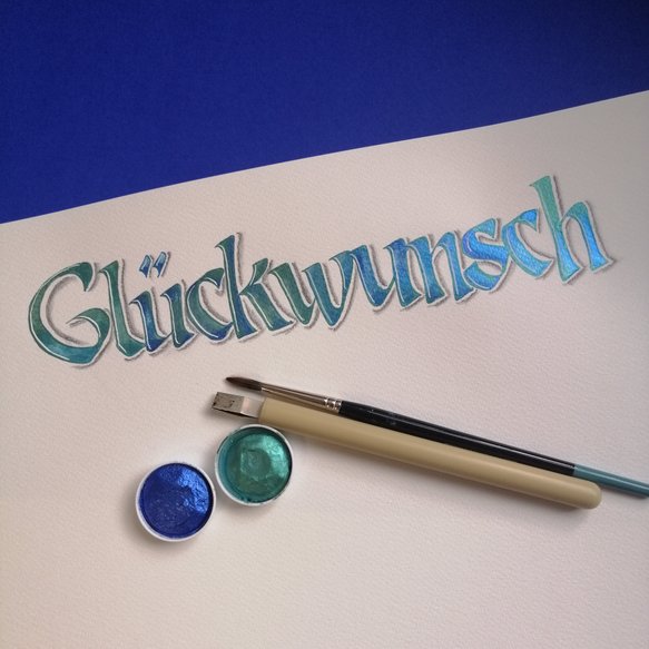 Schriftbeispiel mit Utensilien und Farben